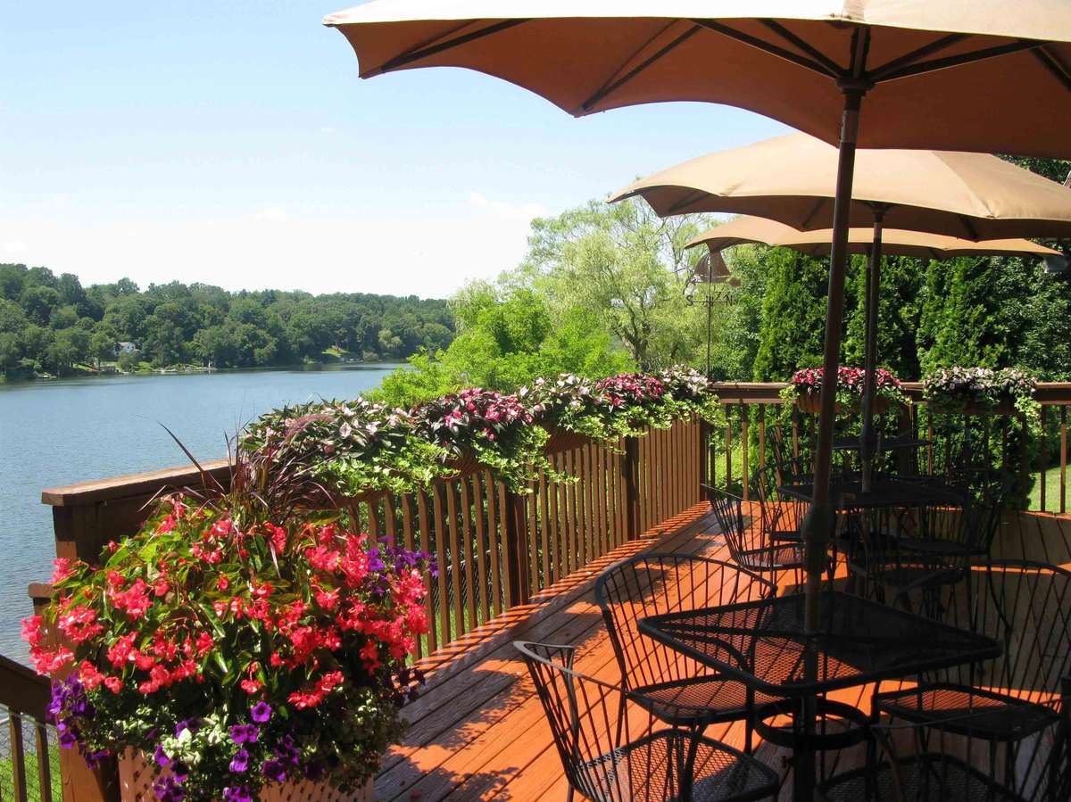 outdoor patio next to a lake with tables, chairs and flowers