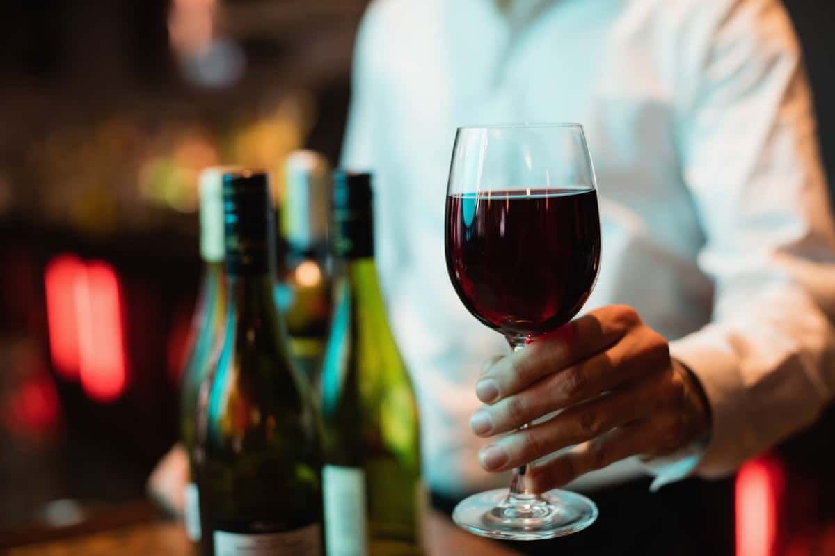 Waiter holding out a glass of red wine