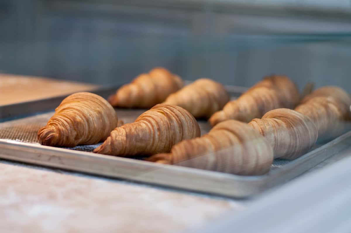 Freshly baked, golden croissants cooling on a tray, with their flaky layers visible.