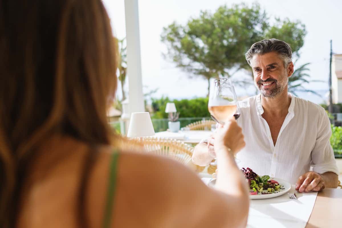 loving-couple-looking-each-other-smiling-while-sitting-table-proposing-toast-together-date-restaurant-street