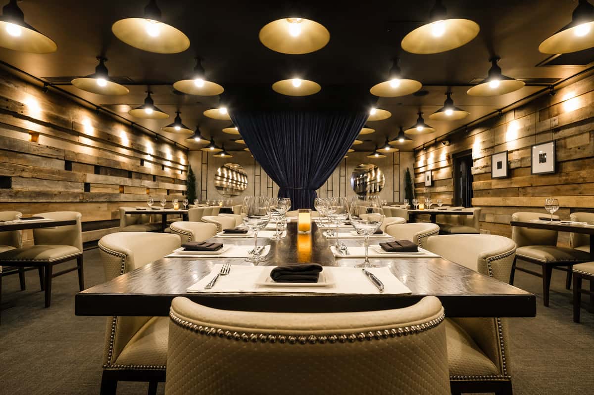 Mishima room event space at Kayne Prime with rustic wood walls, ambient lighting, and plush seating around large tables.