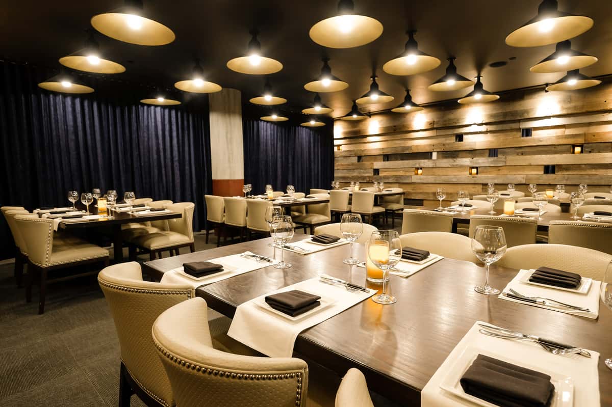 Mishima room event space at Kayne Prime with rustic wood walls, ambient lighting, and plush seating around large tables.
