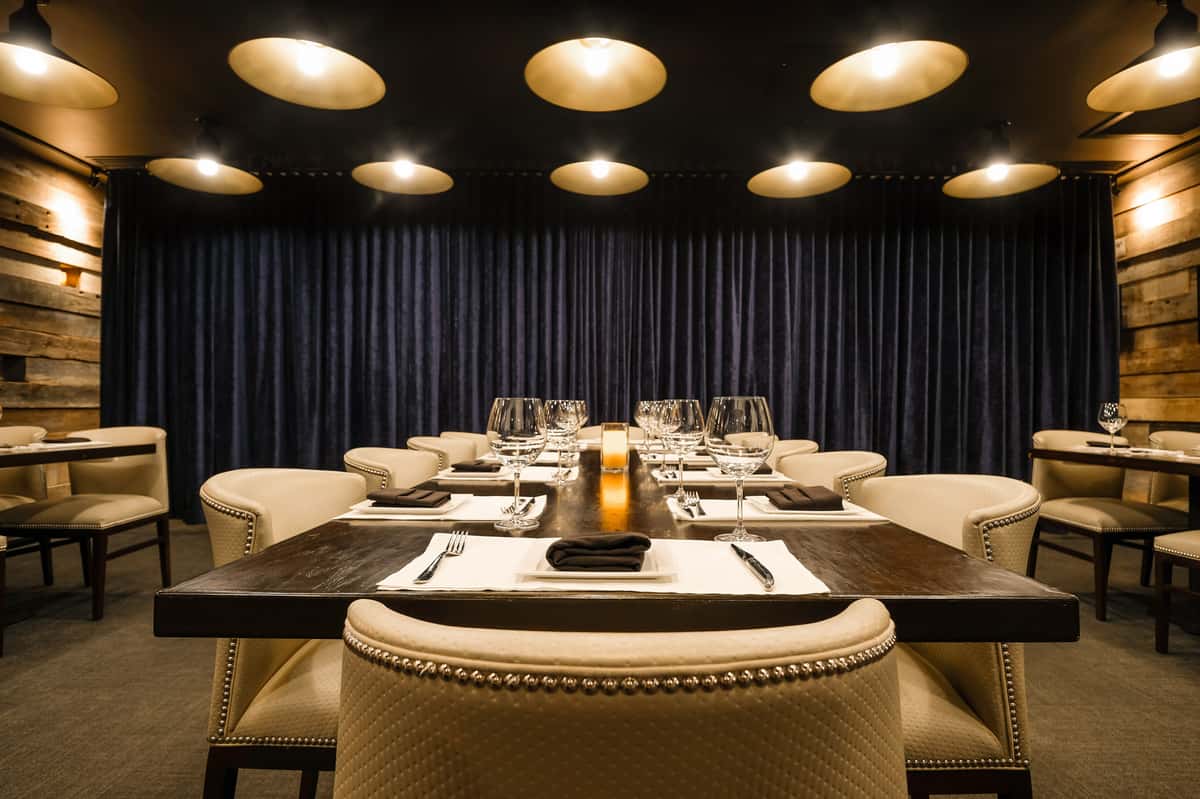 Mishima room event space at Kayne Prime with rustic wood walls, ambient lighting, and plush seating around large tables.