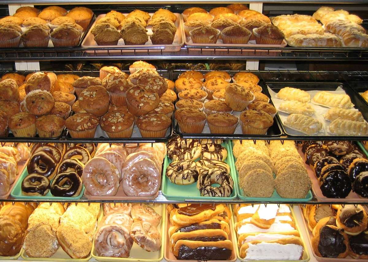 Pastry case filled with a variety of pastries including donuts, cookies, eclairs and muffins.