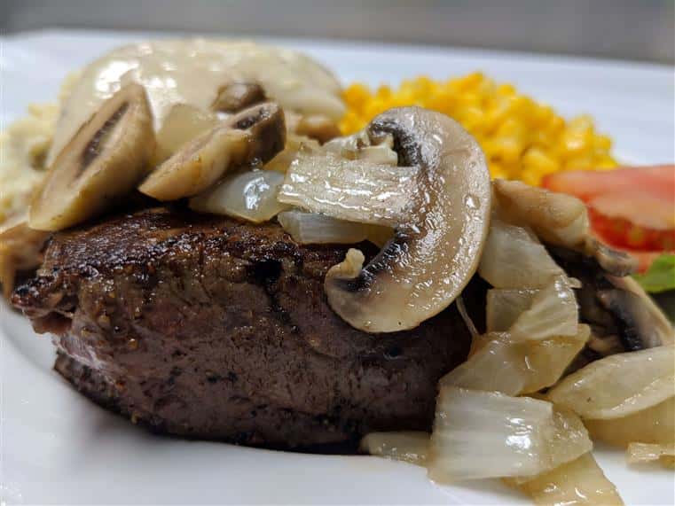 Steak topped with grilled mushrooms and onions