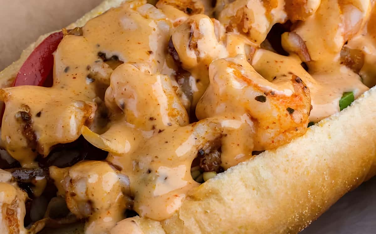 A close-up of a sandwich filled with grilled shrimp and topped with a creamy sauce.