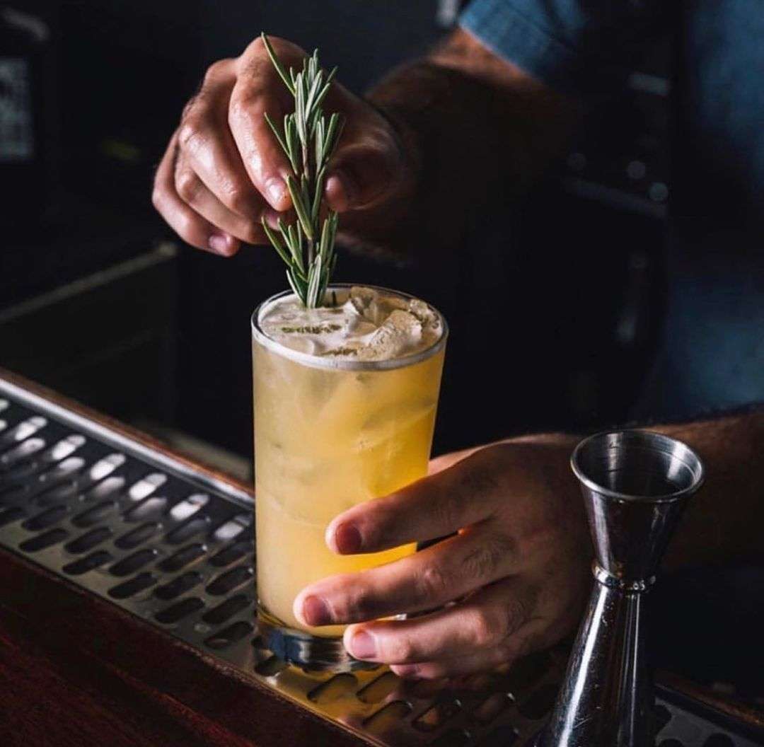 Hand placing a garnish in a cocktail