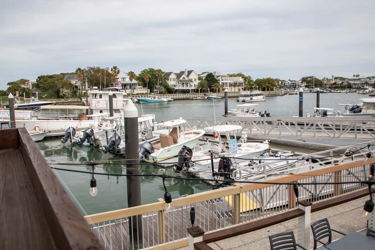 waterfront marina view with docked boats and coastal homes seen from a restaurant patio