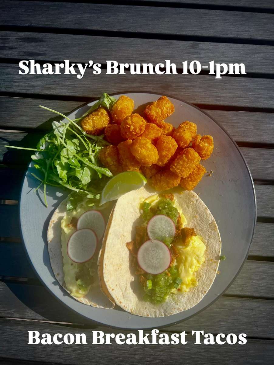 Bacon breakfast tacos topped with salsa verde and radish slices served with crispy tater tots and fresh greens