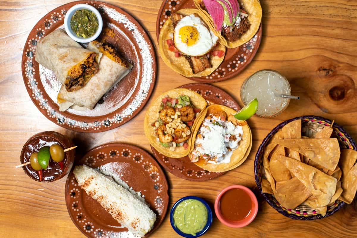 Hero image of a spread of Mexican breakfast food on a wooden table