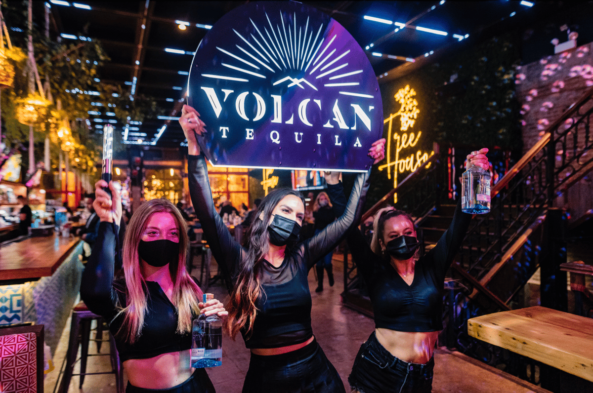 women holding volcan tequila sign