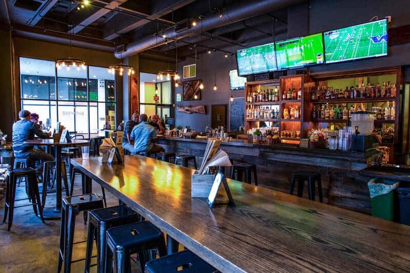 Lively bar and dining area at Hardwood Bar & Smokery with craft beverages, large-screen TVs, and a vibrant atmosphere for private parties and receptions