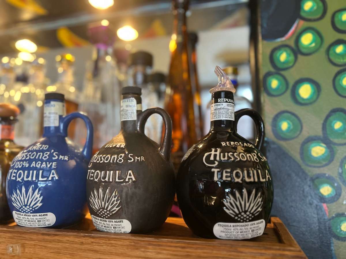 Decorative tequila bottles displayed on a shelf in a restaurant.