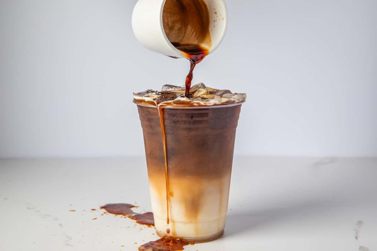 A topping being poured on a cup of espresso