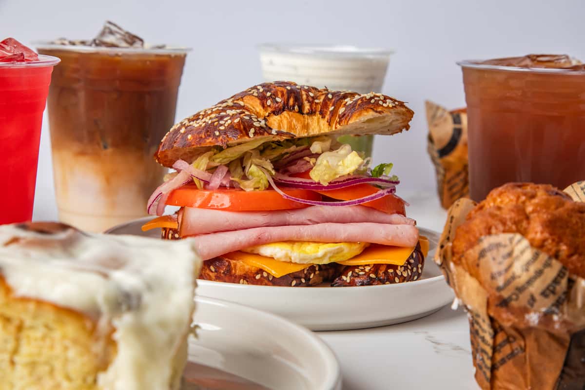 Croissant sandwich surrounded by drinks