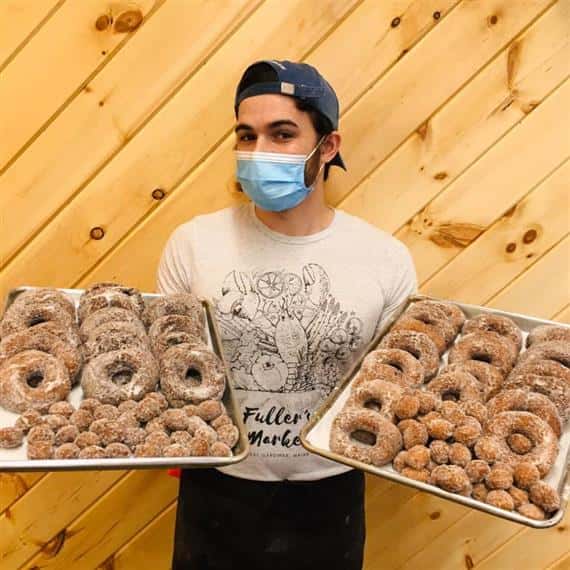 employee holding trays of donuts and donut holes