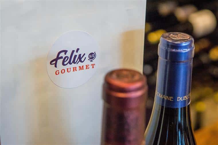 two wine bottles in front of a to-go bag