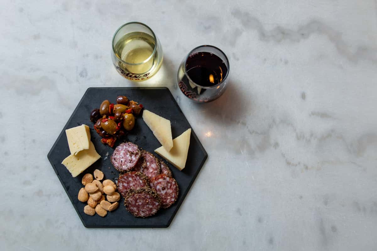 charcuterie items on a plate with wine glasses