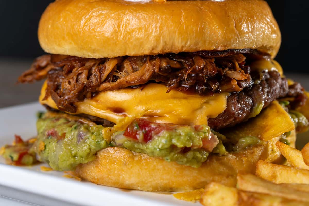 Tasty pulled pork cheeseburger with guacamole on a fresh bun.