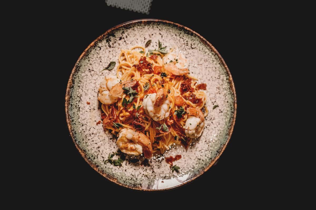 A mouth-watering shrimp pasta dish beautifully presented on a speckled ceramic plate, perfect for a gourmet meal.