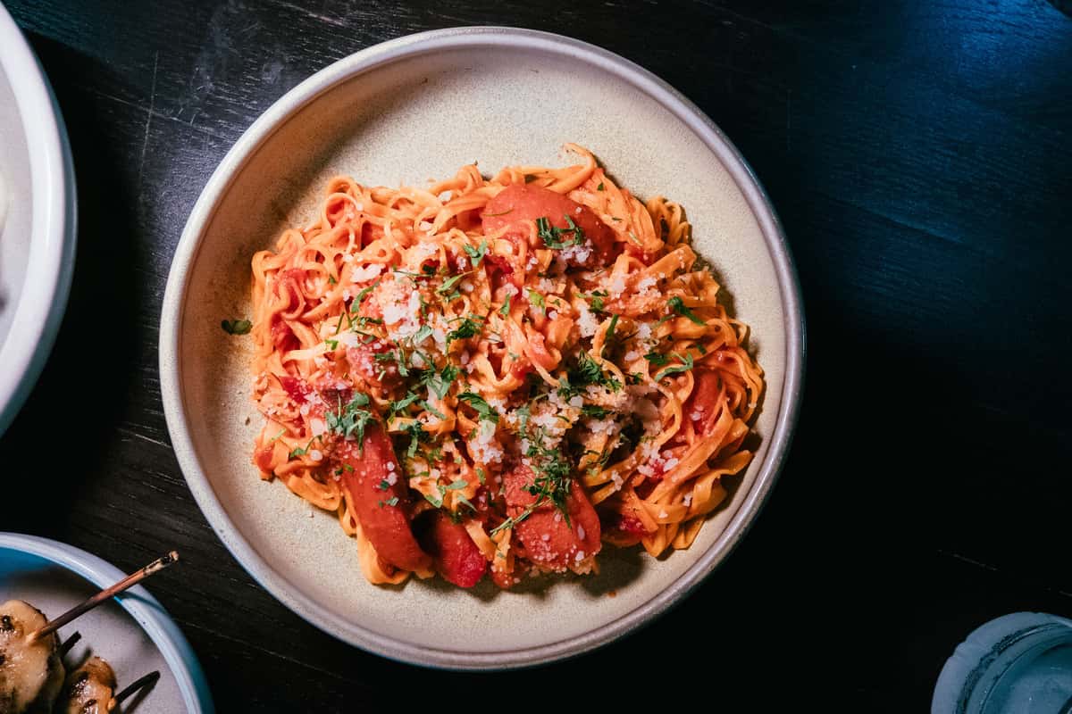 Delicious bowl of tagliatelle pasta topped with tomato sauce, cheese, and herbs.