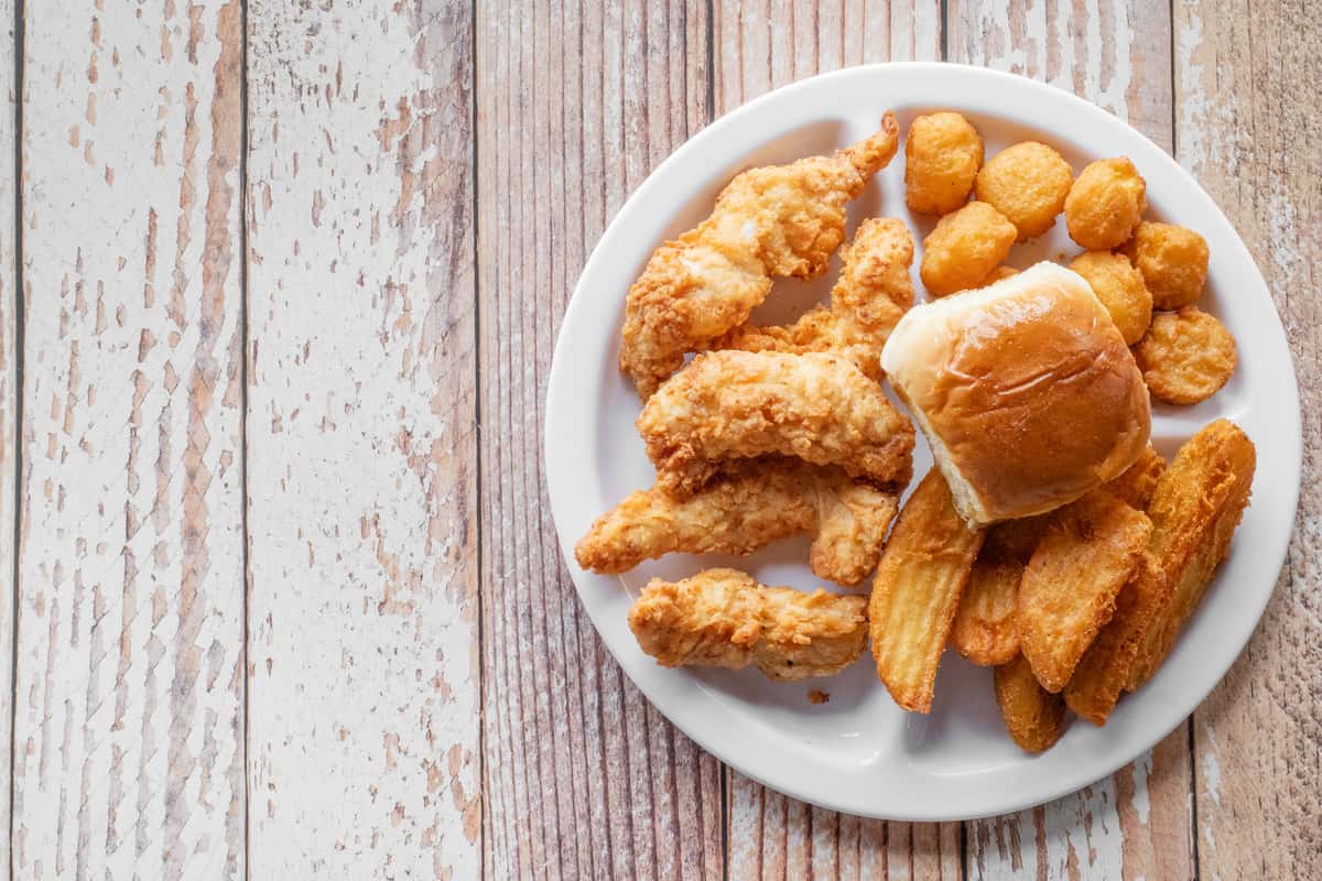 A plate of crispy golden chicken fingers served on a white plate