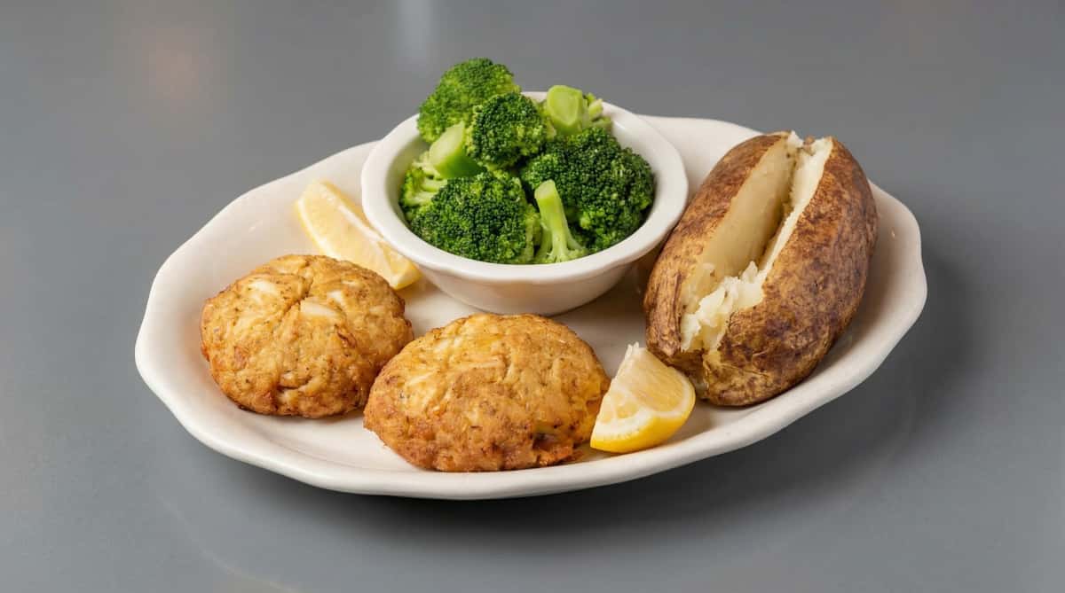 Crab cakes served with steamed broccoli, baked potato, and lemon wedges