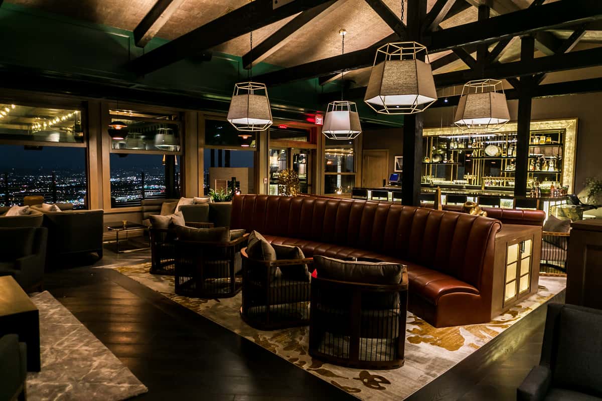 Upscale restaurant lounge interior with leather banquette seating, ambient lighting, and panoramic nighttime city views