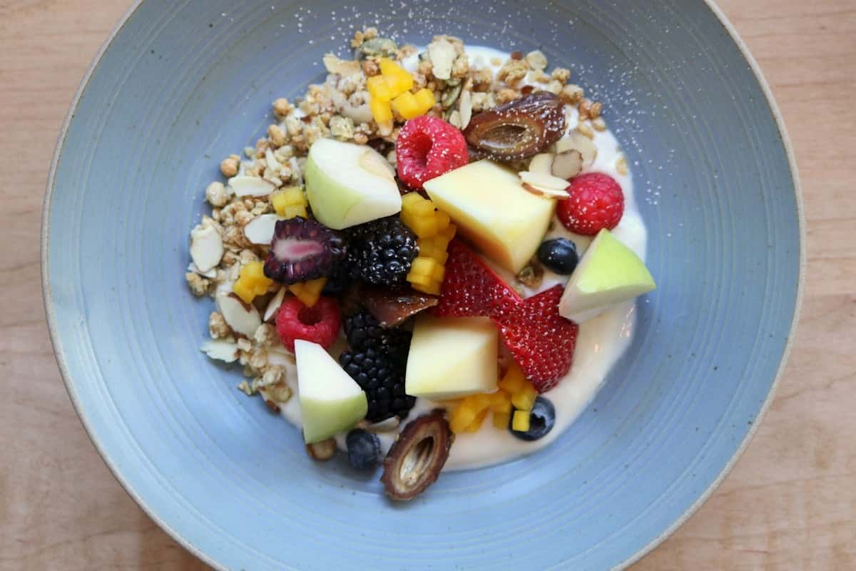 La Biónica dessert bowl with fresh tropical fruits, granola, berries and toppings, served on a blue plate, a vibrant dish at Zaranda Houston