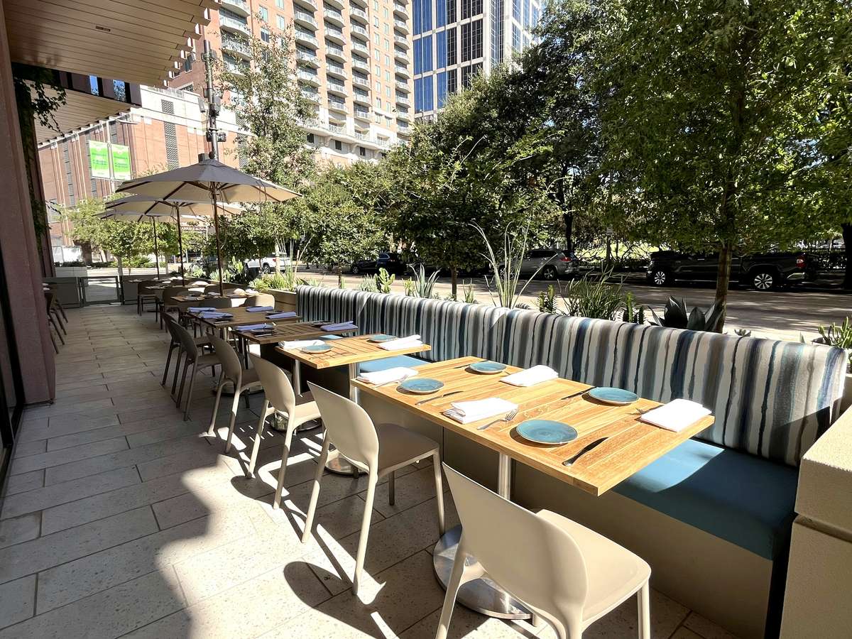 Outdoor patio dining area at Zaranda Houston with tables and chairs set up in a lush urban setting, perfect for al fresco dining experiences