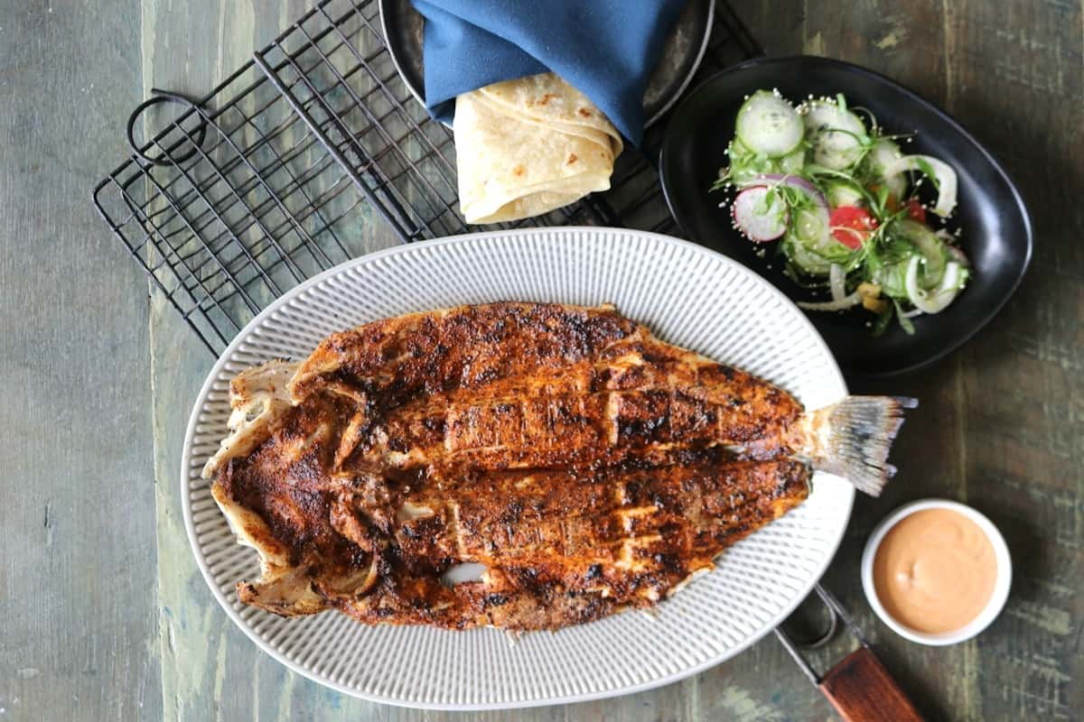 Pescado Zarandeado entero a la parrilla con especias y hierbas, servido en plato blanco, platillo icónico del menú de Zaranda Houston