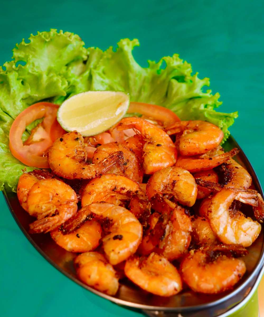 A platter of fried shrimp garnished with lettuce, tomato and a lime wedge at The Salty Rim, a fun beach restaurant.