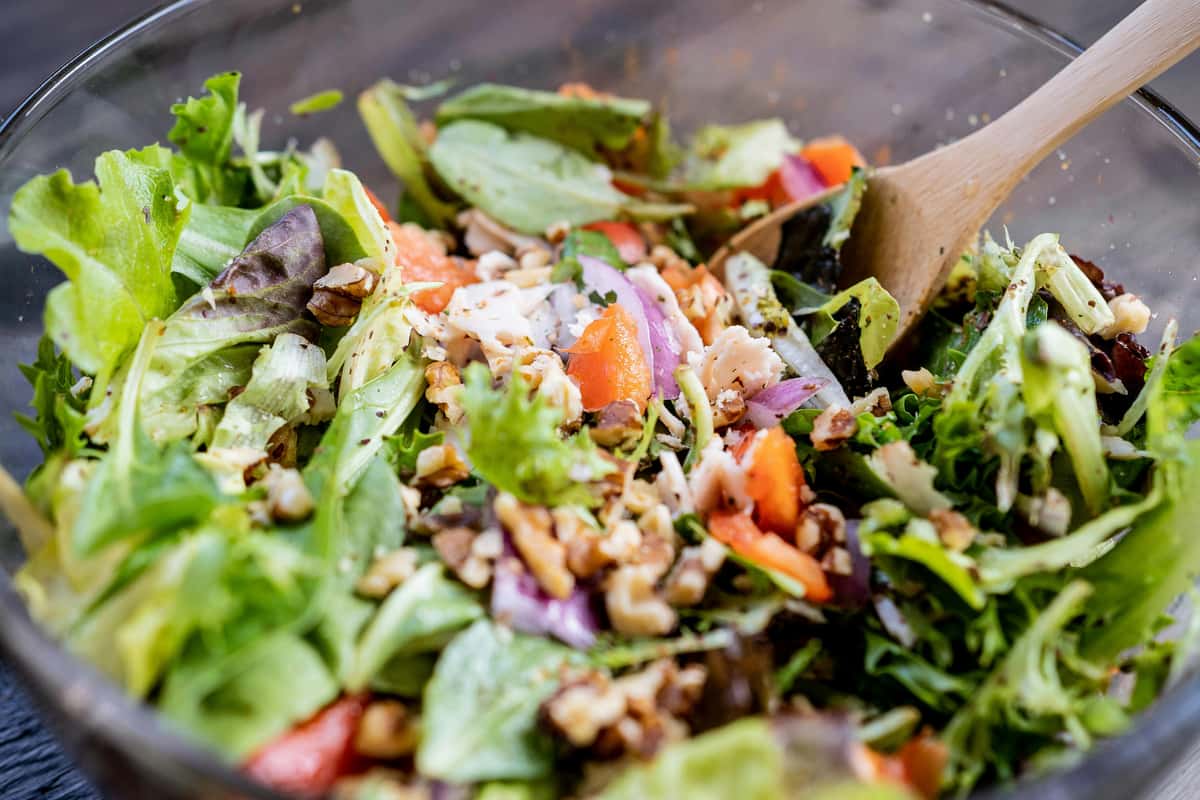 Mixed green salad with grilled chicken, walnuts, red onion, and fresh vegetables, tossed in a light dressing for a healthy, gourmet restaurant dish.
