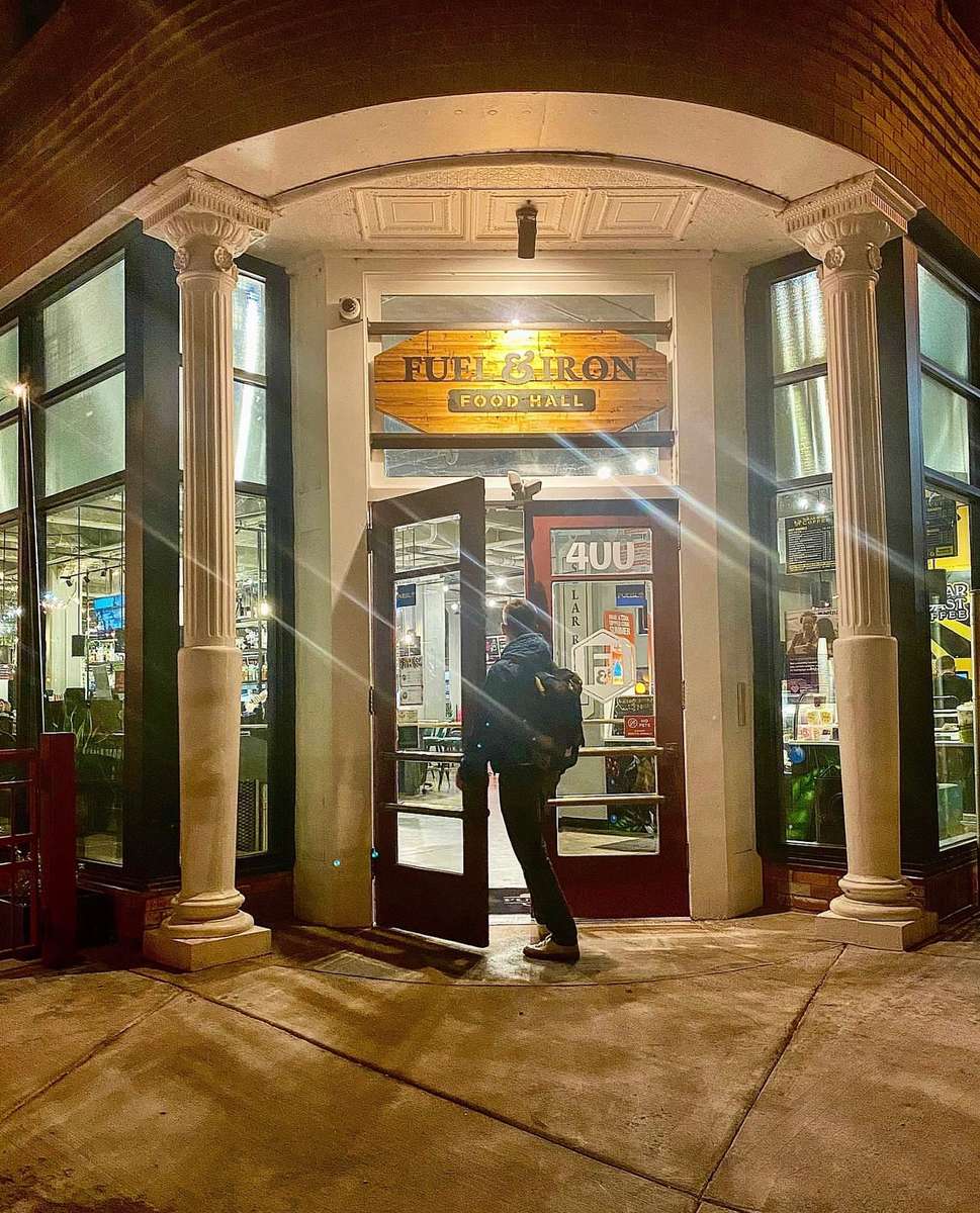 the entrance to Fuel & Iron with a man opening the door, at night time