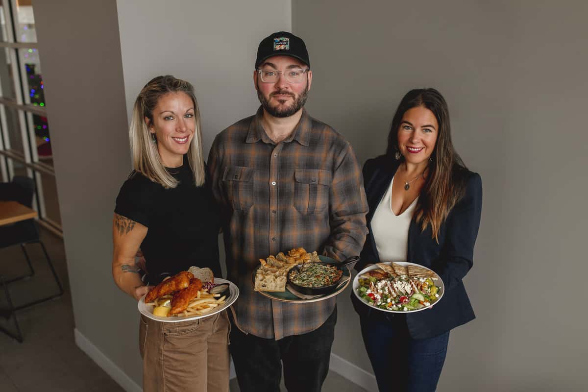 Two women and a man presenting dishes