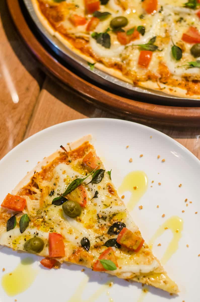 a whole pan of pizza and a slice on a plate
