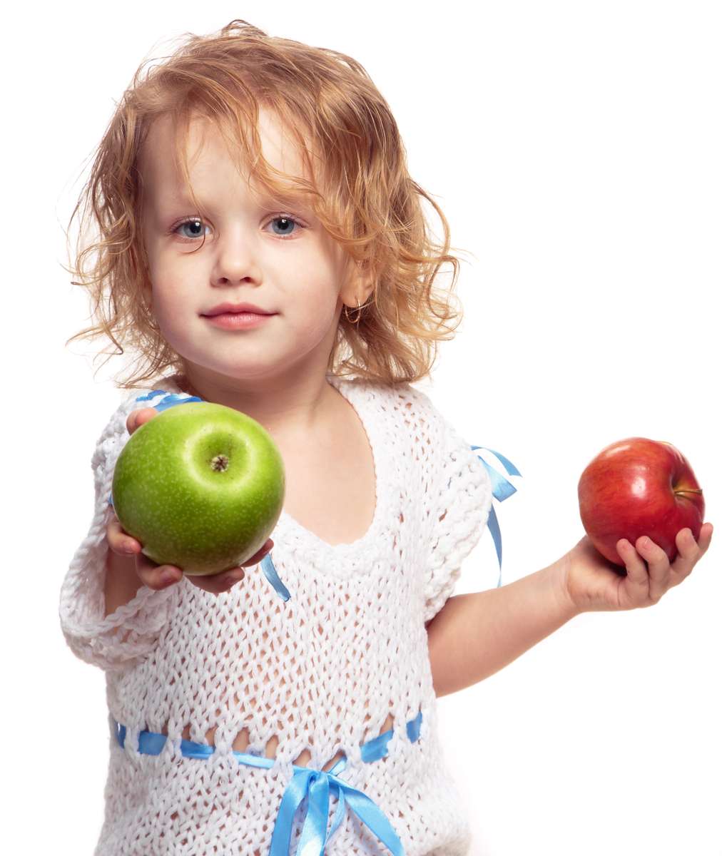 child holding two apples out as if offering them to someone