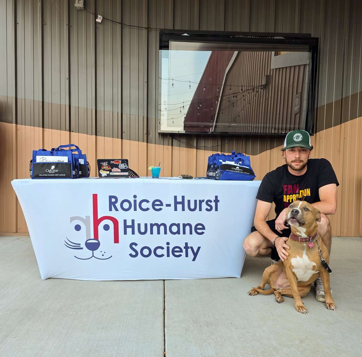 Roice-Hurst Humane Society representative kneeling with a brown and white dog at our Yappy Hour event at Riverside Pub in Grand Junction, supporting local animal rescue with Hera The Dog Vodka specials