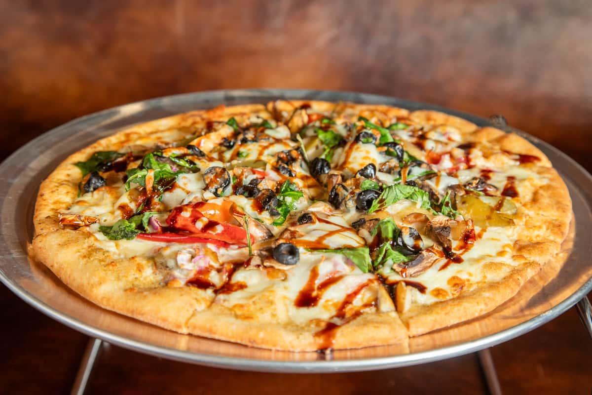 Fresh Garden Glow Pizza loaded with colorful vegetables, herbs, and gooey cheese at Riverside Pub at River City Sport Plex