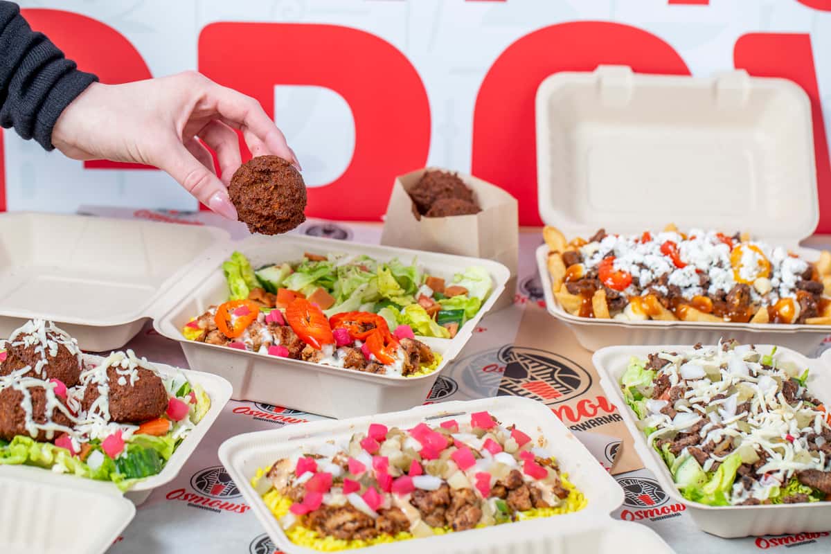 Hand grabbing a falafel from a container of food