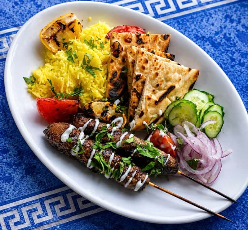 a plate of Greek meat skewers served with rice and veggies
