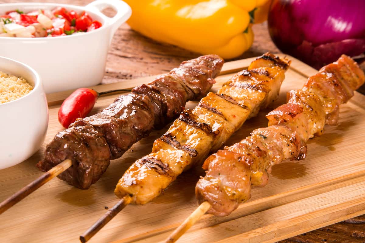 Beef, chicken and lamb kabobs on a wooden tray