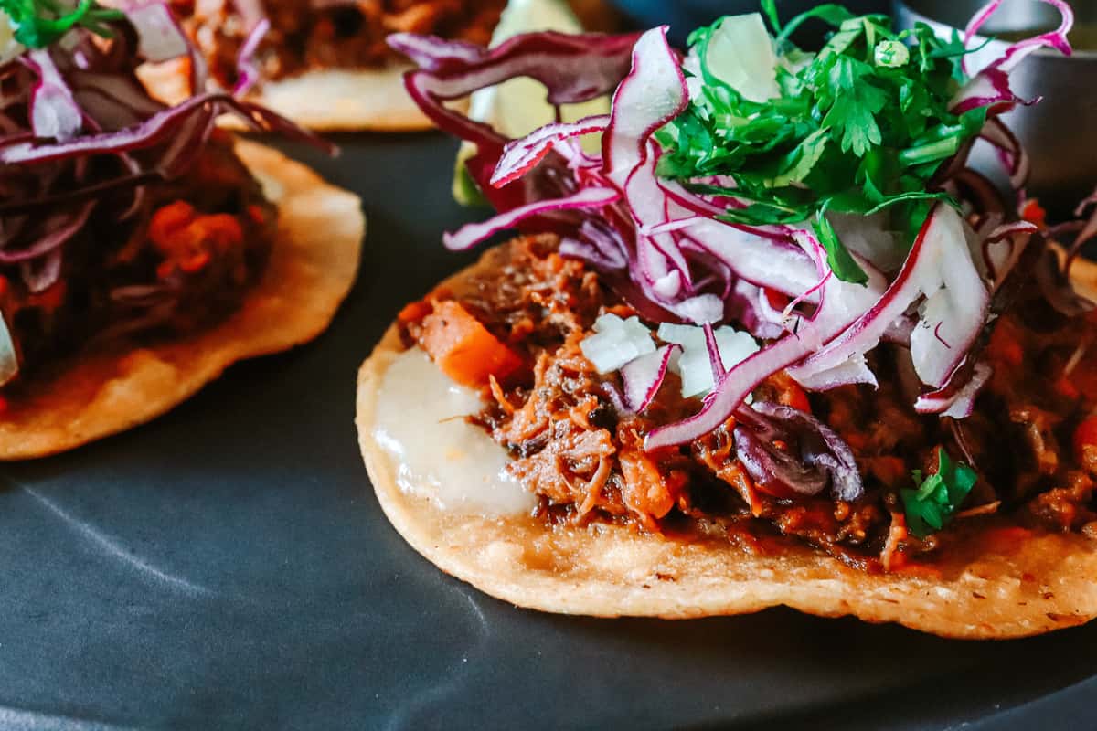 Authentic Mexican street taco topped with slow-cooked shredded beef, pickled red onions, fresh cilantro, and queso fresco on a soft corn tortilla.