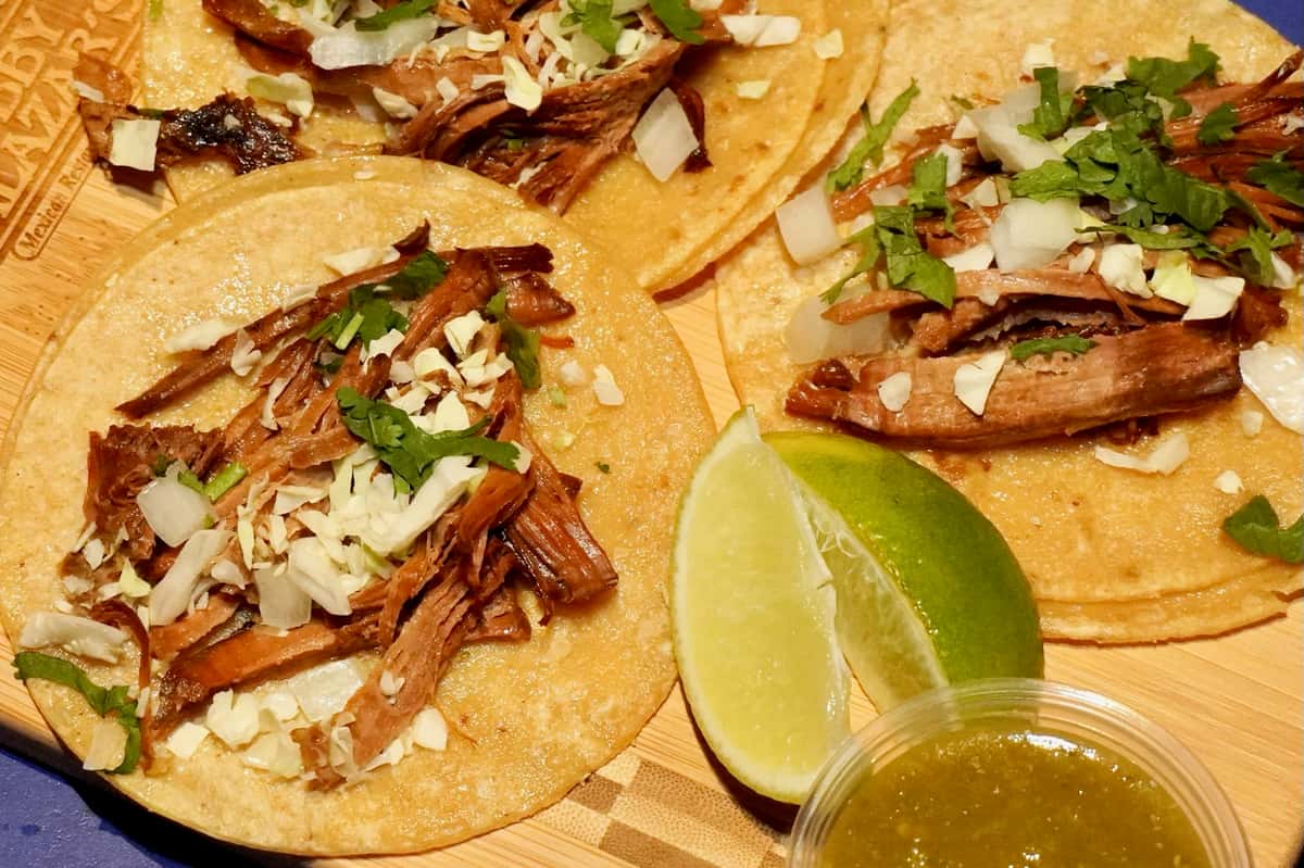 Authentic Mexican street tacos topped with seasoned grilled meat, fresh cilantro, onions, and queso fresco, served with a lime wedge and salsa verde at Bobby Salazar's Mexican Restaurant & Cantina.