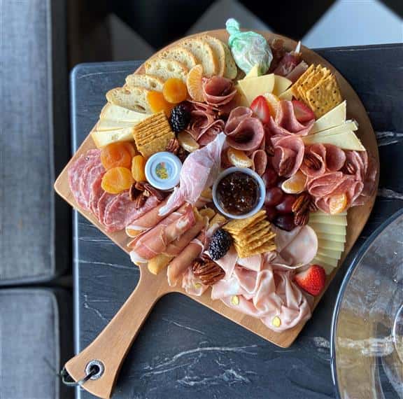 charcuterie board with meats, cheese, crackers, and fruit