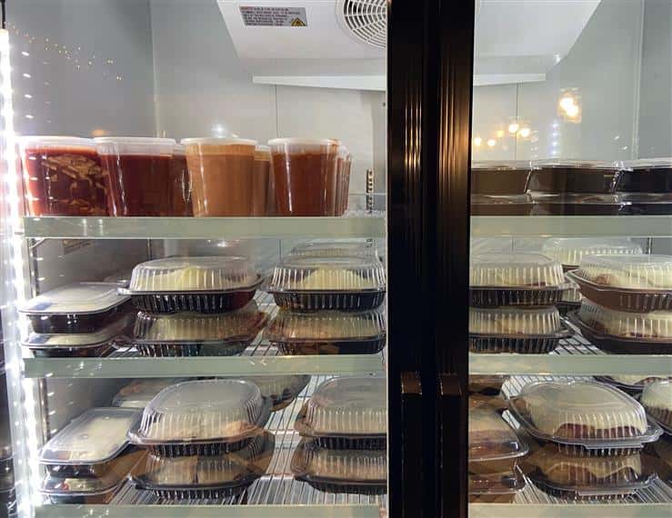 assortment of prepared meals and sauces on shelves in the fridge