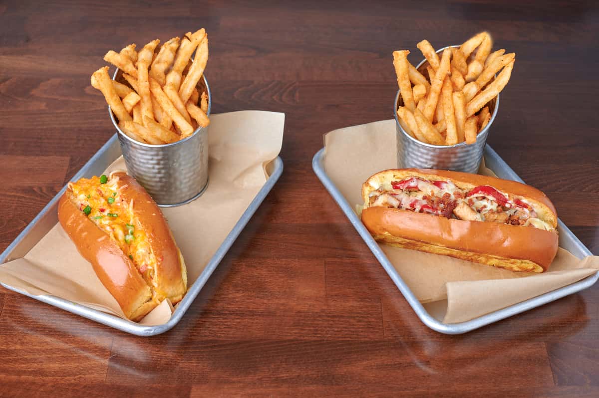Two sandwich rolls on trays, including Wings Over USA's popular lobster roll. Each tray includes a bucket of crispy French fries.