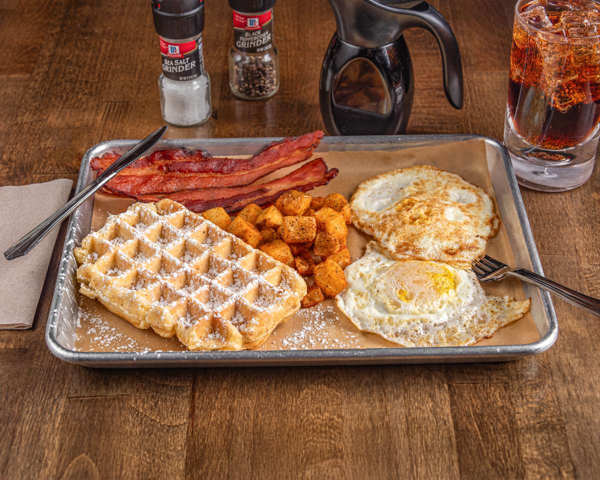 Two eggs any style, bacon or sausage, hash brown patty and waffle with syrup on the side. Can add toppings to waffle at additional charge