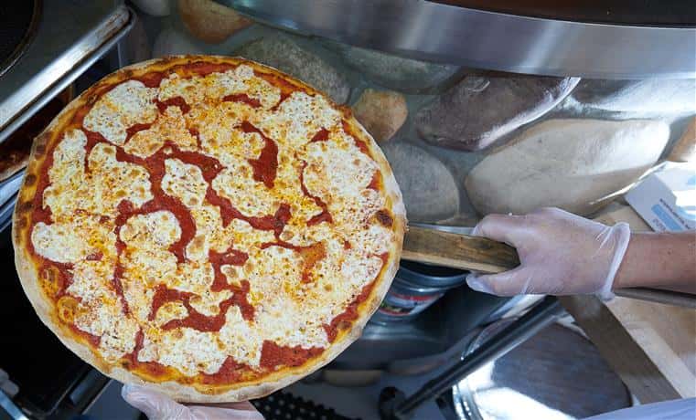 chef taking cheese pizza out of the oven