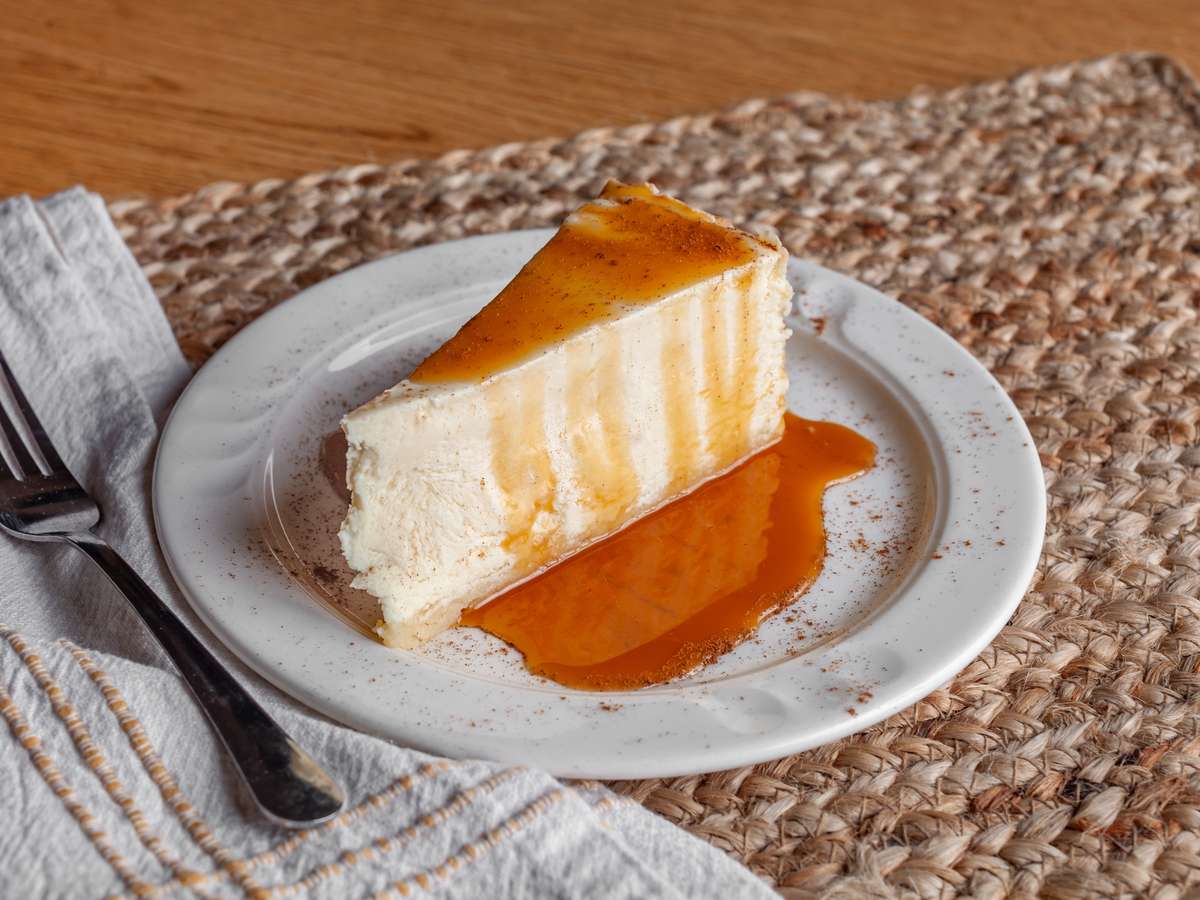 Slice of creamy cheesecake with caramel drizzle on a plate at Arroyo's Grill in Atascadero